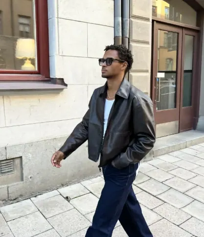 Creator wearing sunglasses and a leather jacket on a city street
