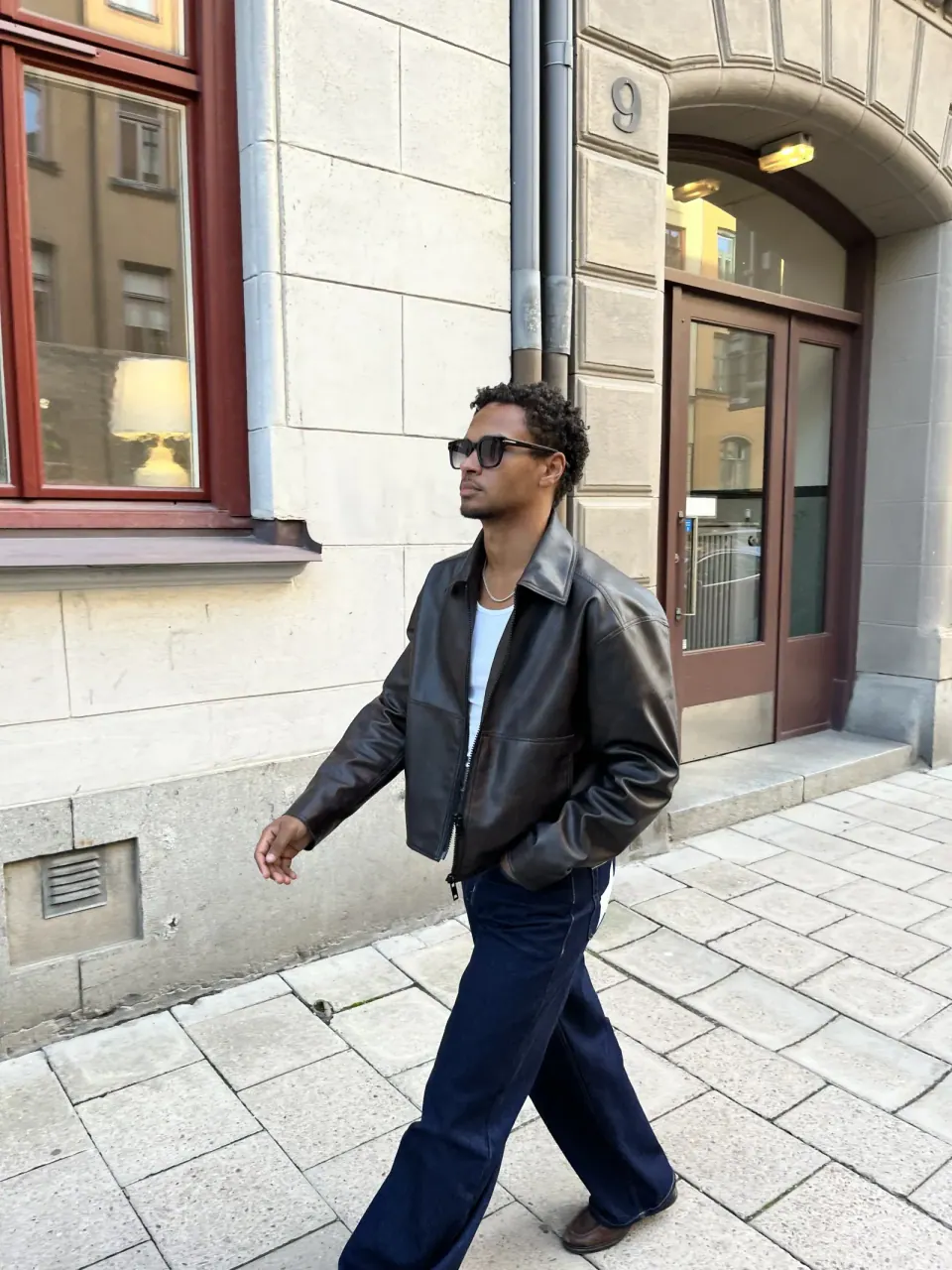 Creator wearing sunglasses and a leather jacket on a city street